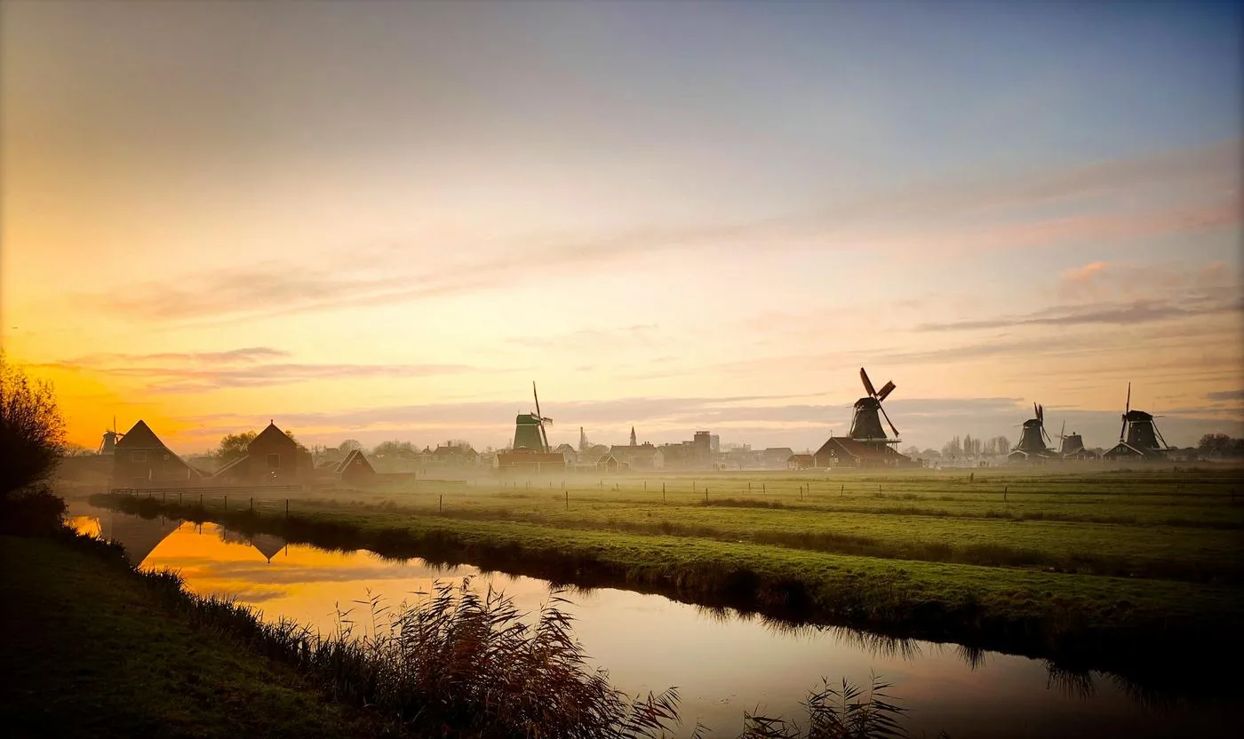 Foggy sunrise over the windmills and polder canal at Zaanse Schans, the Netherlands