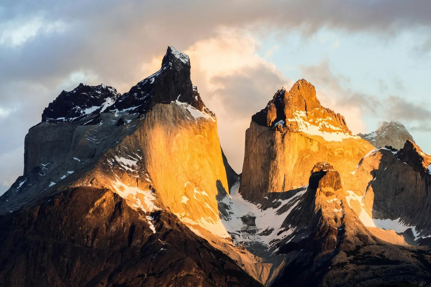 Two jagged granite peaks glow orange in evening light above patches of snow.
