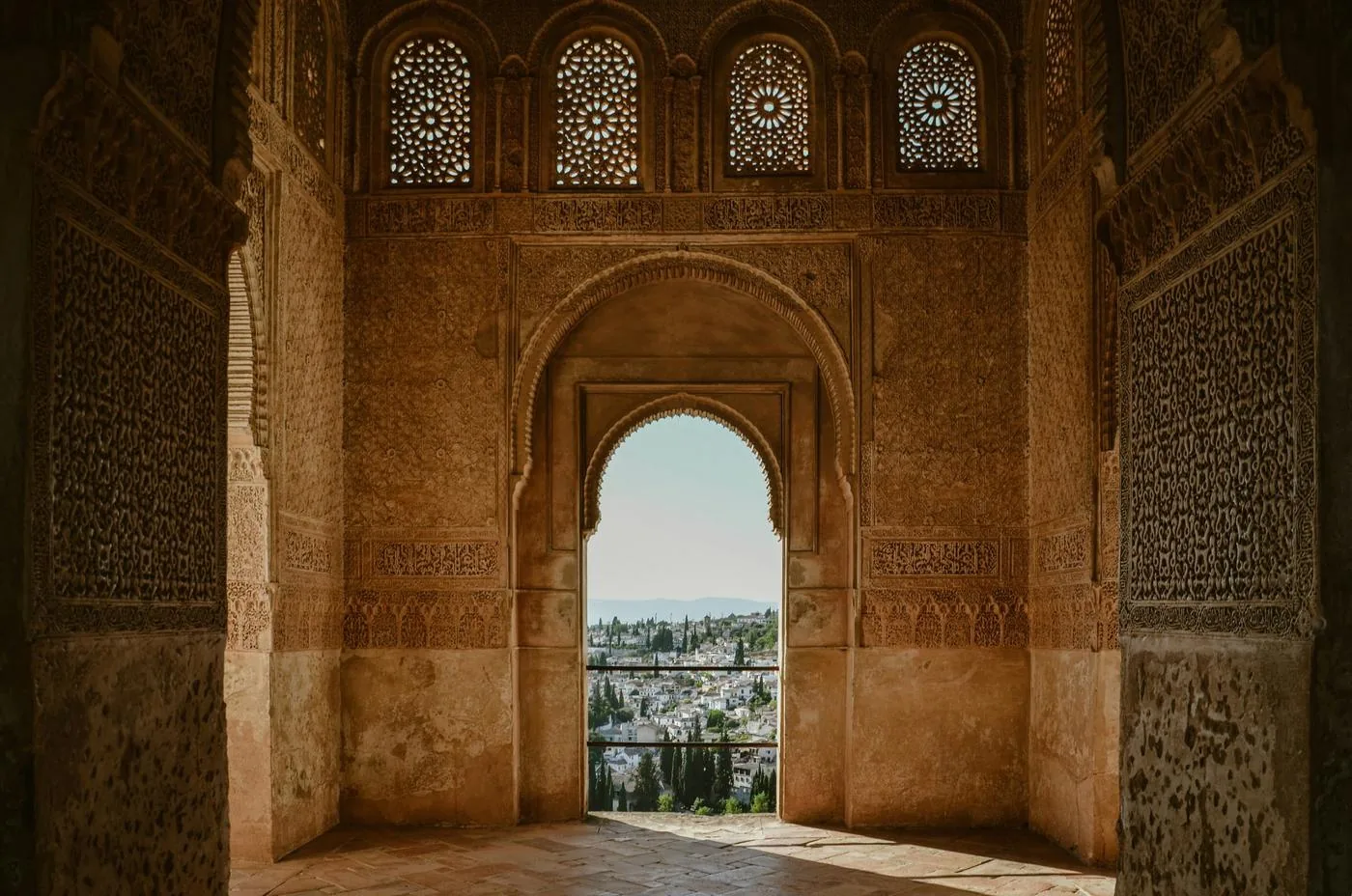 An arched window in an ornate Moorish palace frames a view over the city.