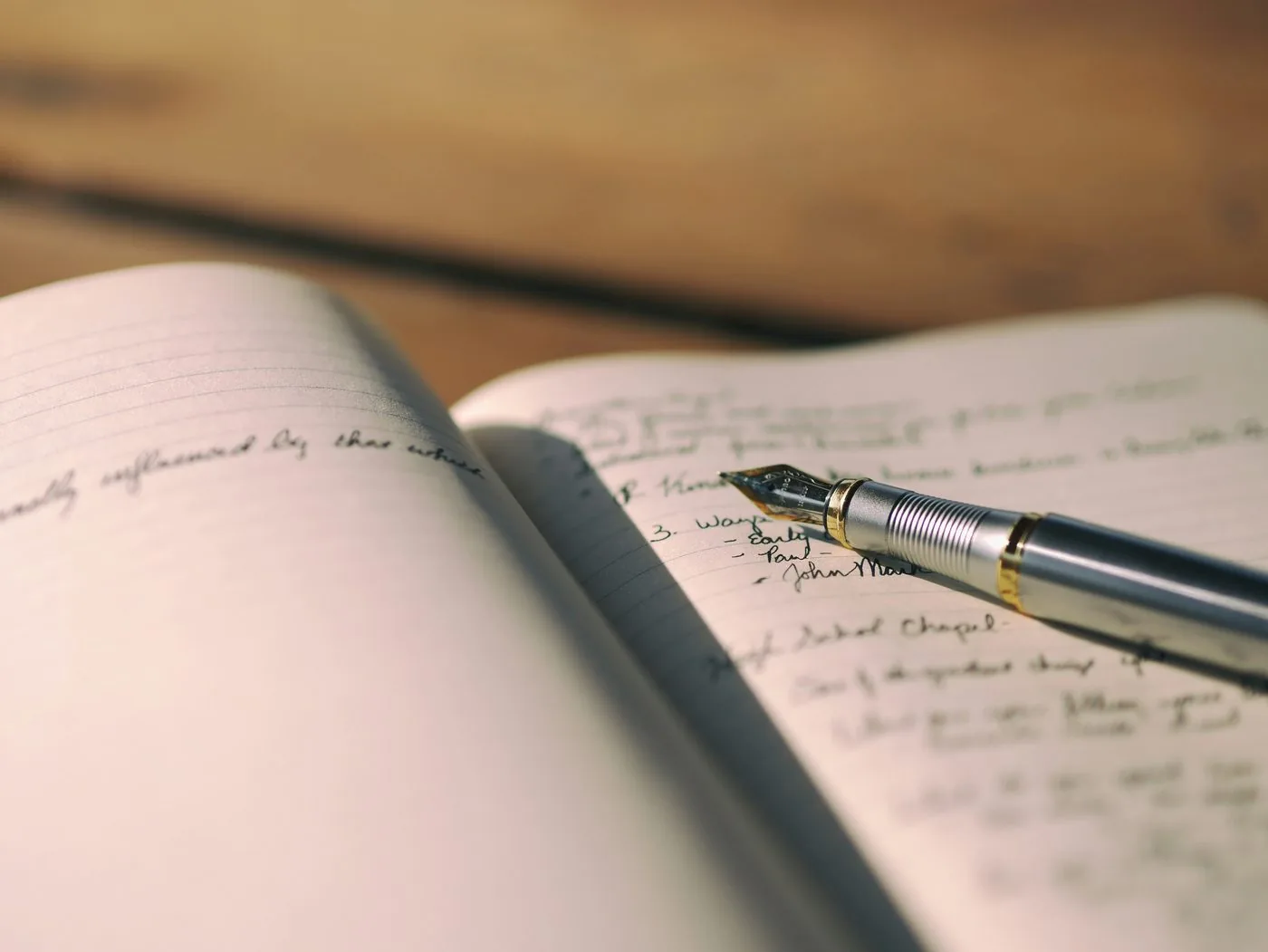 A fountain pen rests on an open journal filled with handwriting.